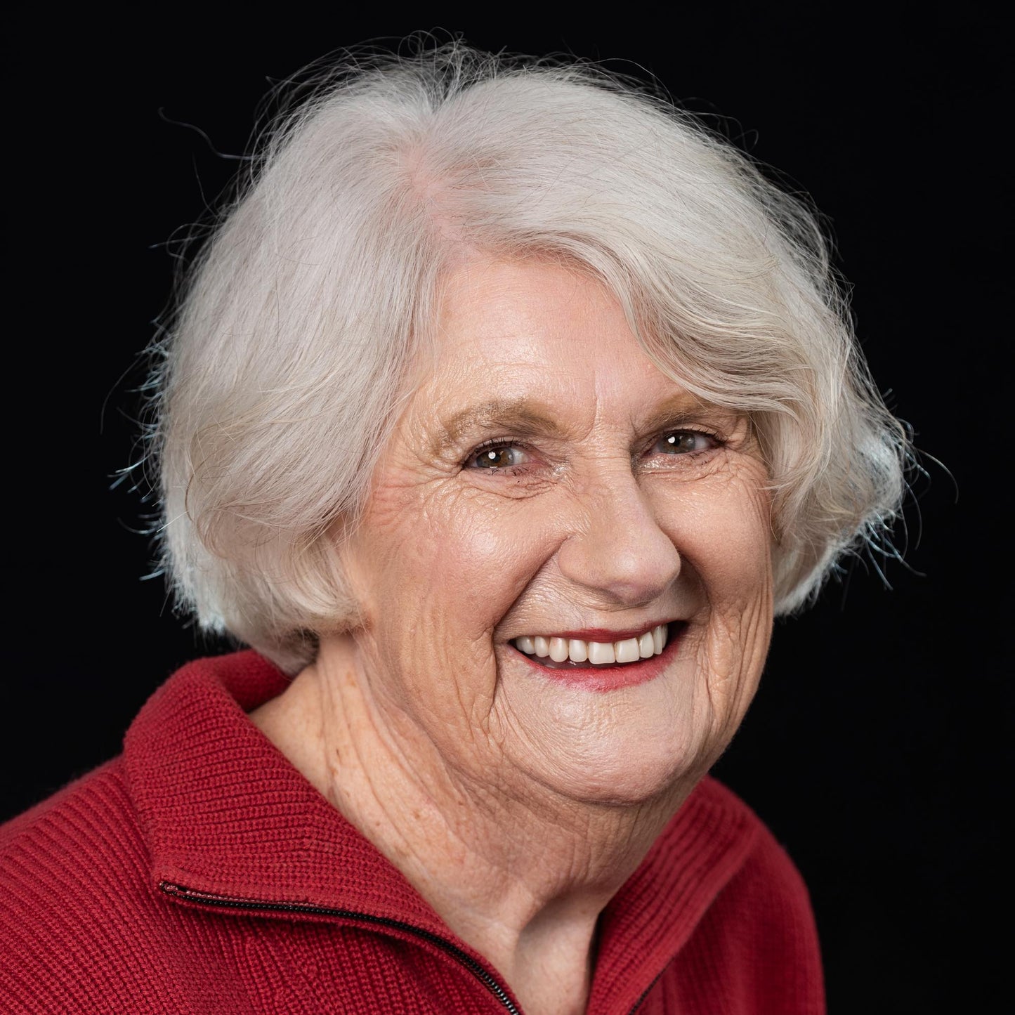 oder woman grey hair on black background wearing cameo lipstick and compelling foundation