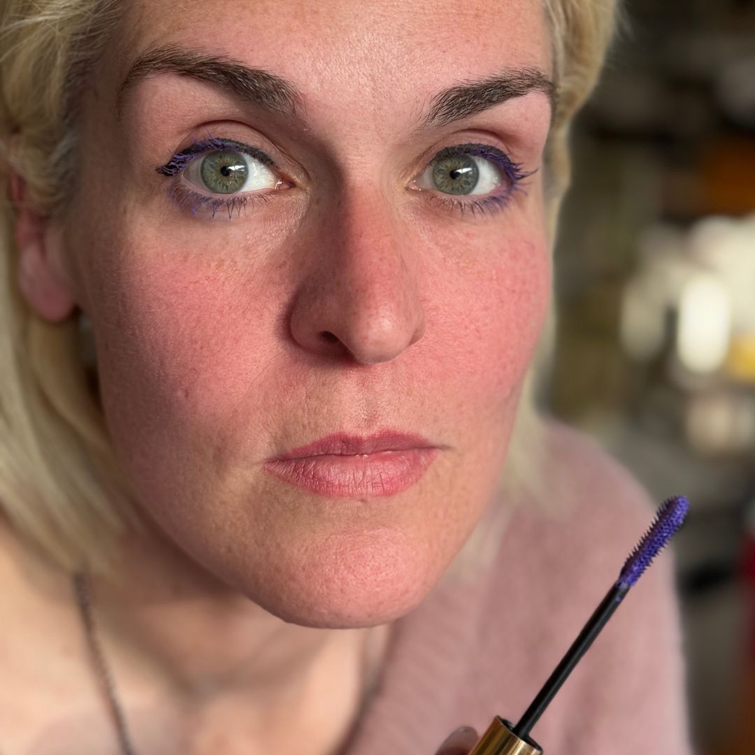 Violet Purple mascara on Caucasian woman, holding mascara wand