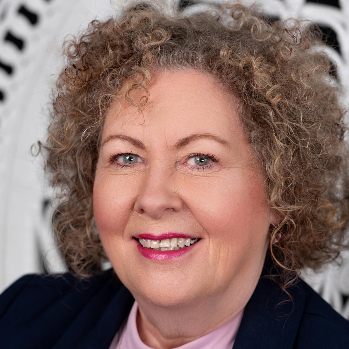 curly haired mouse brown woman in her 60s wearing radiant foundation - pink unertone with peaching tenacuty blush and ecru very light brown eyebrow pomade