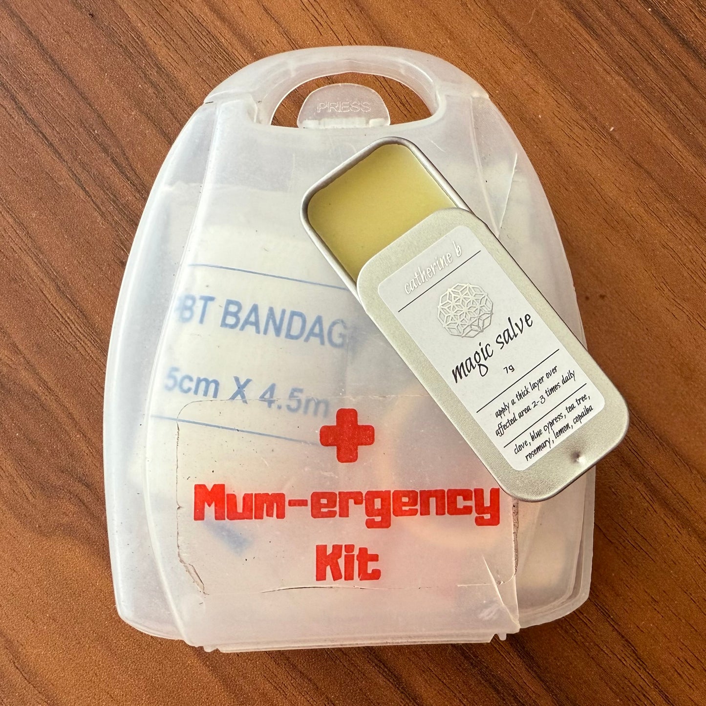 Mum-ergency kit with bandages and salve on a wooden surface