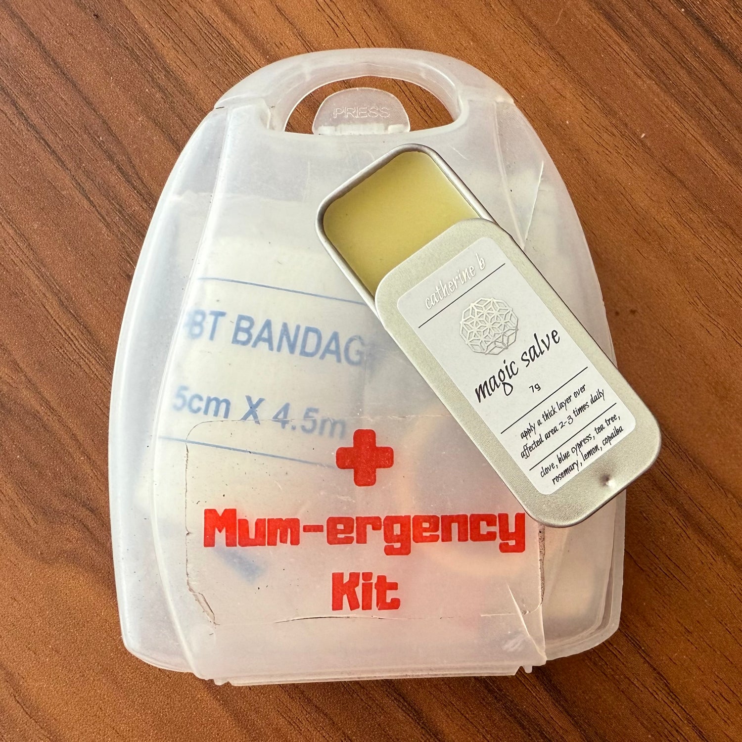 Mum-ergency kit with bandages and salve on a wooden surface