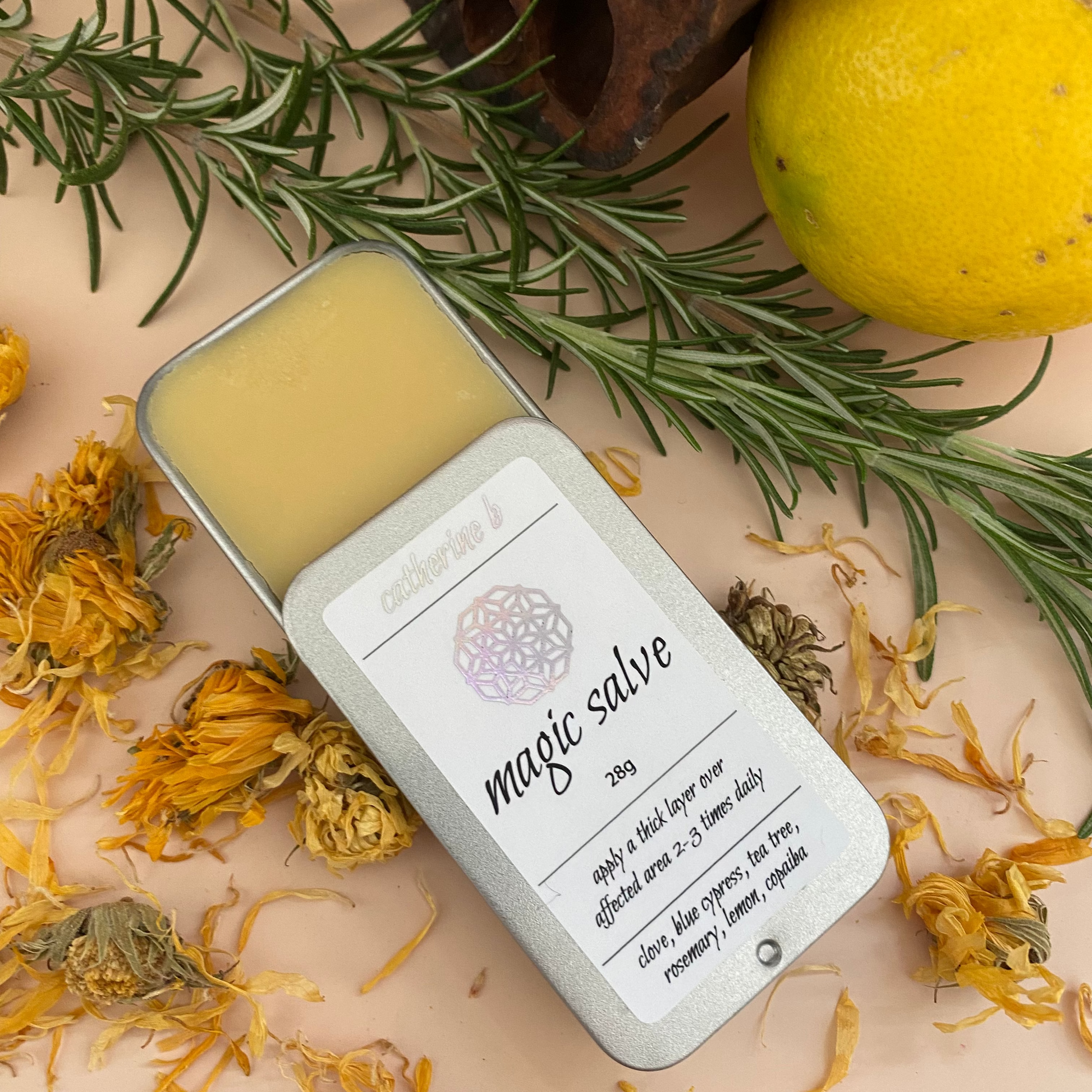 Large tin of 'magic salve' with herbs and flowers on a beige background