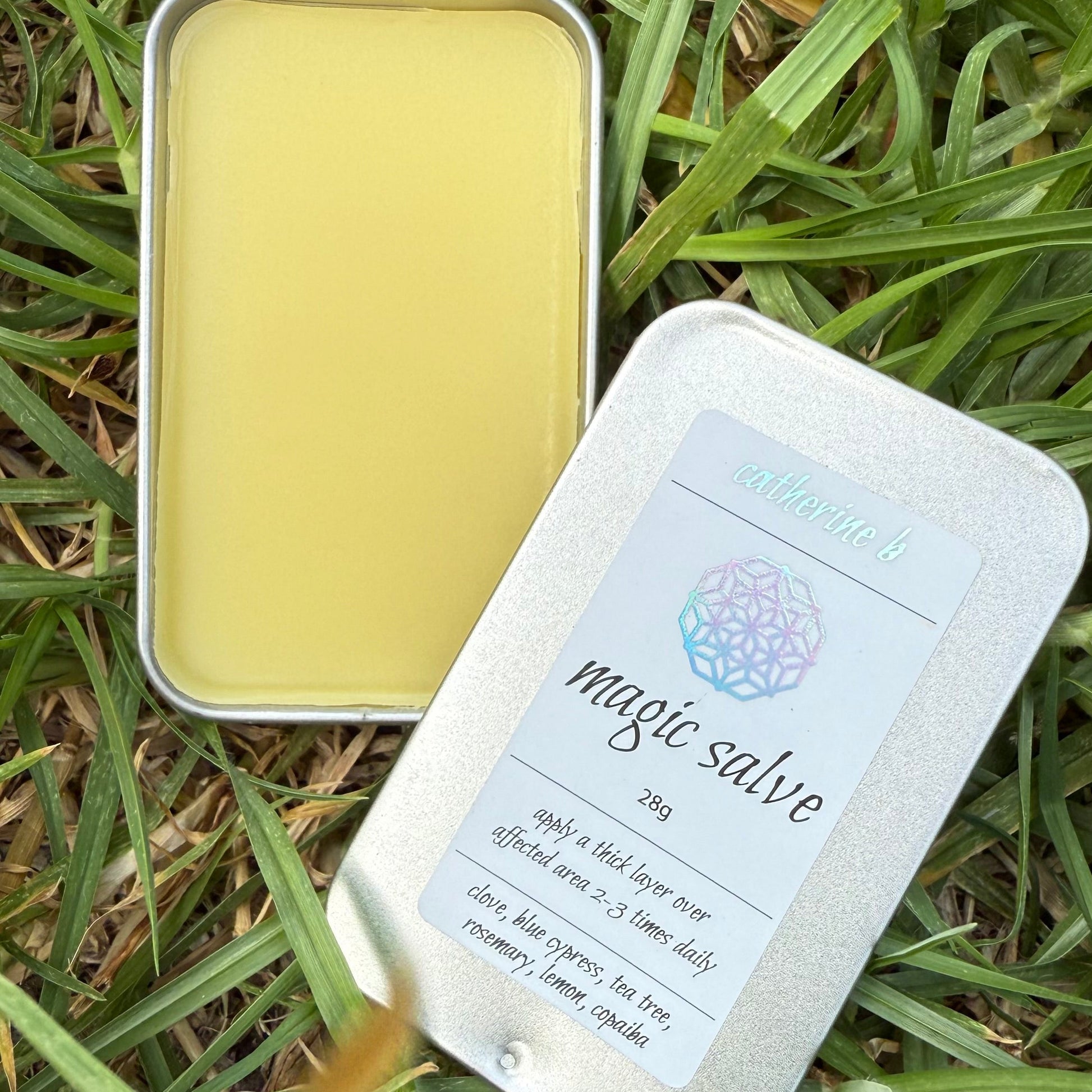 Metal tin with yellow magic salve and a label on grass