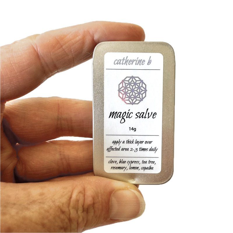Hand holding a medium container labeled 'magic salve' by Catherine B.