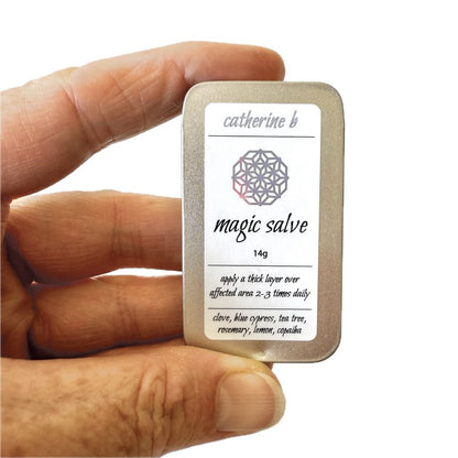 Hand holding a medium container labeled 'magic salve' by Catherine B.
